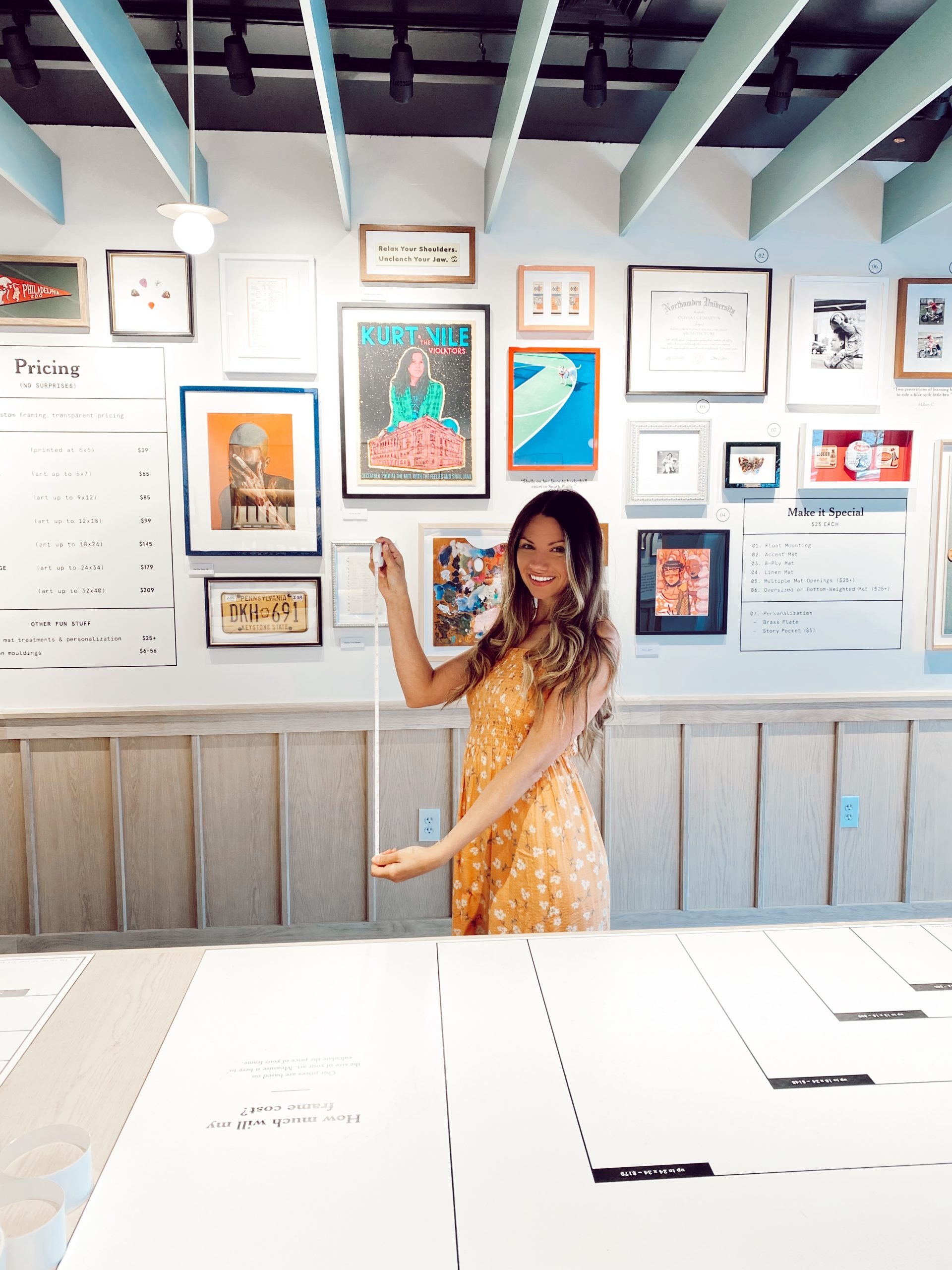 Create the perfect gallery with Framebridge of a woman holding up a measuring tape in the Framebridge Store. 