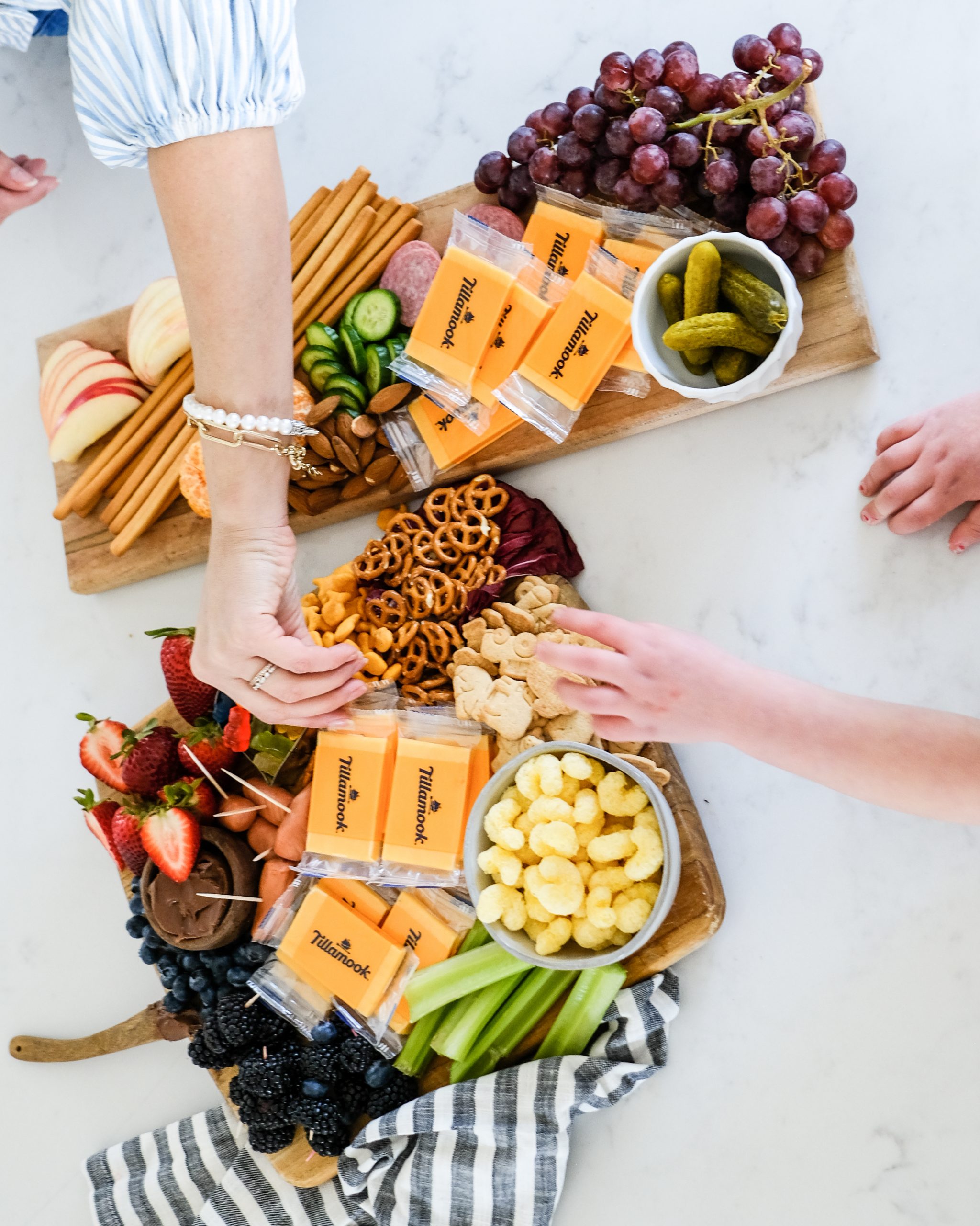 a snack board with popcorn, cheese, apples and snacks for kids with kids hands in the photo