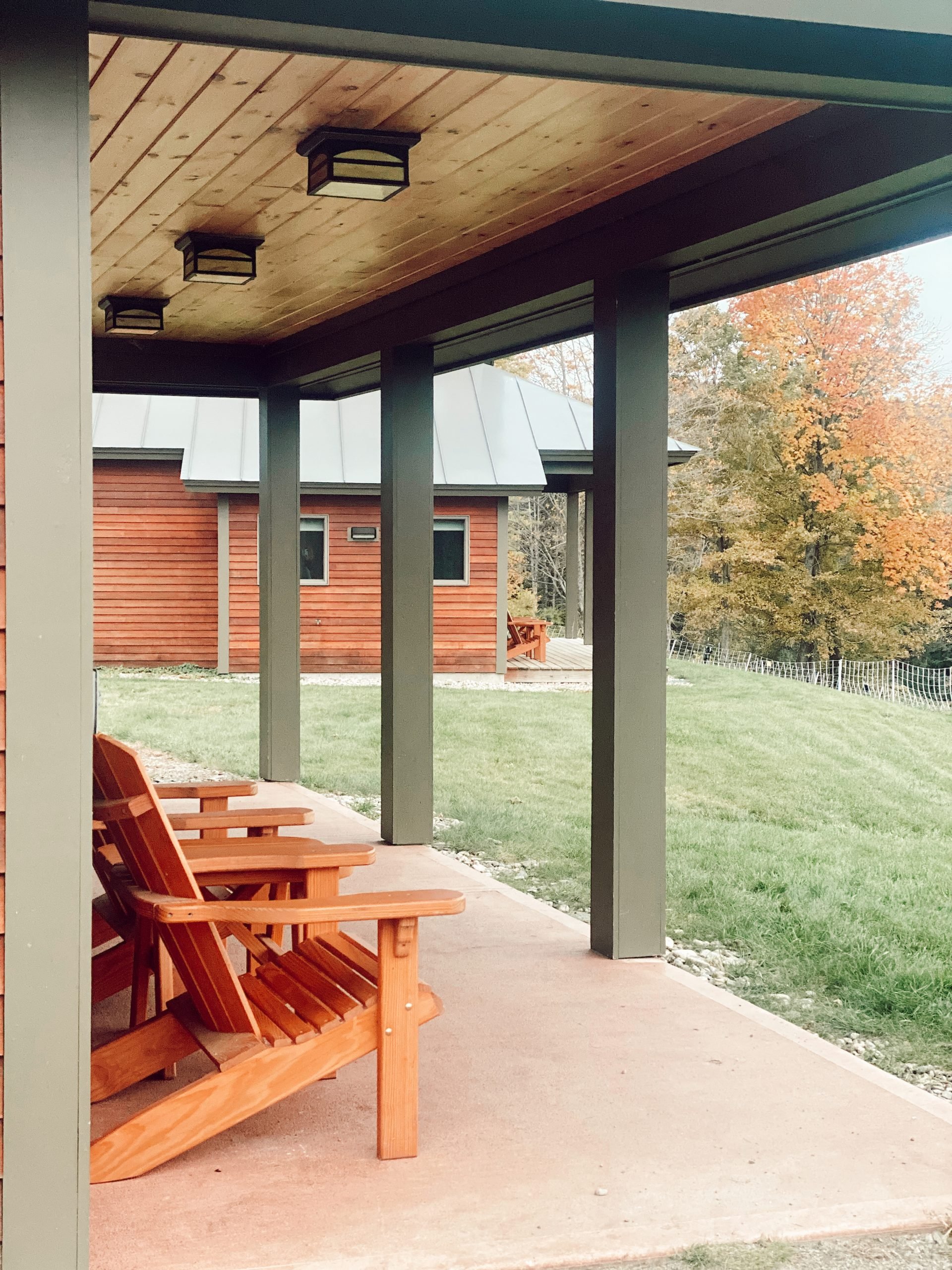 two wooden chairs sit on a cabin porch