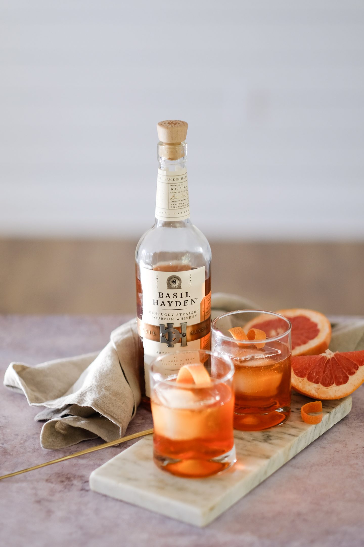 a brightly colored orange cocktail with a bottle of Bourbon in the background.