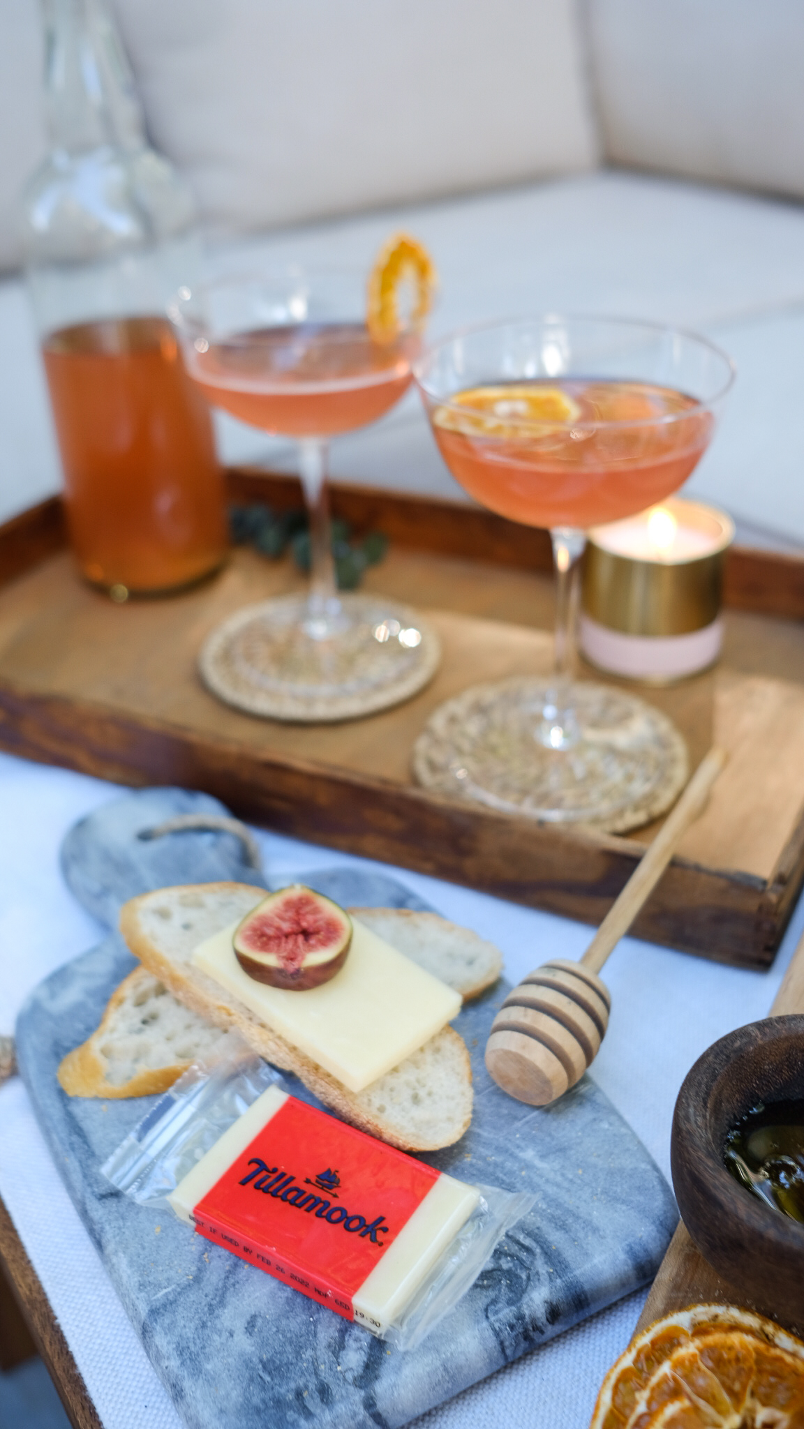 a cheese tray spread with cheeses, figs, nuts and brightly colored drinks