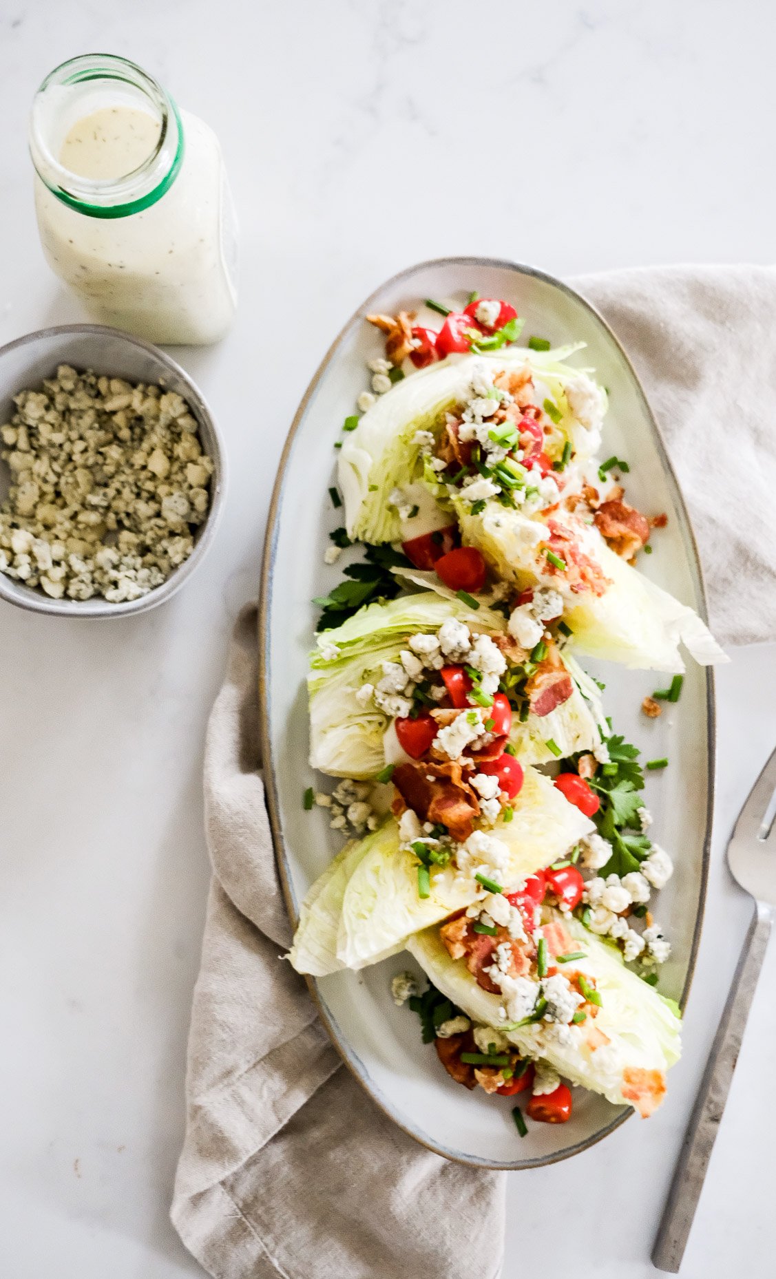 a classic wedge salad with a bowl of blue cheese crumbles