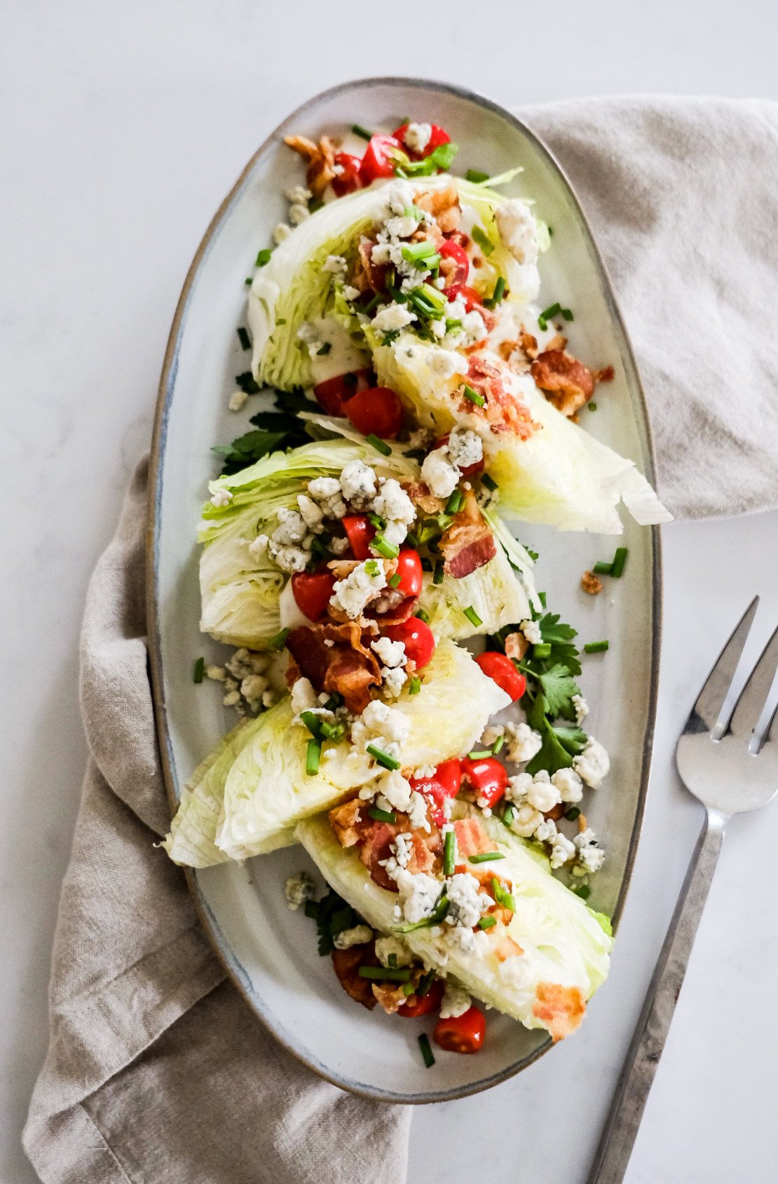 Classic Wedge Salad with Ranch Dressing placed on a white oval dish with serving fork