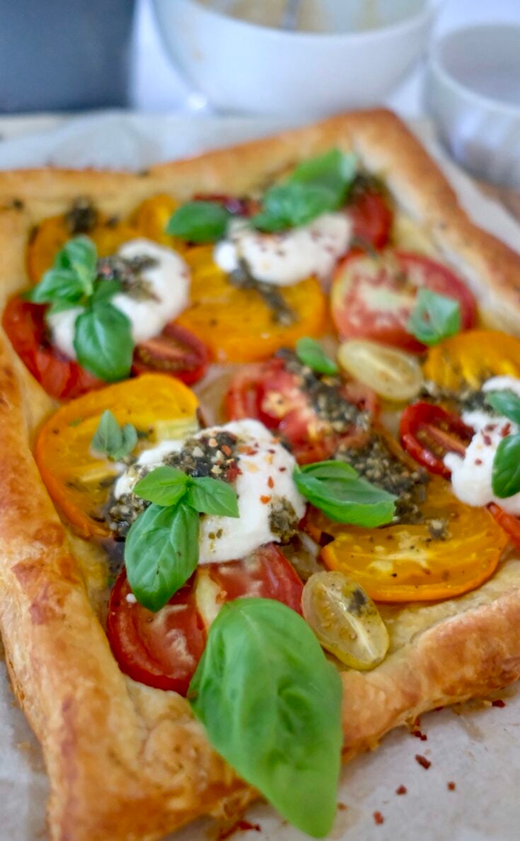 brightly colored tomatoes with basil leaves on a tomato tart recipe.