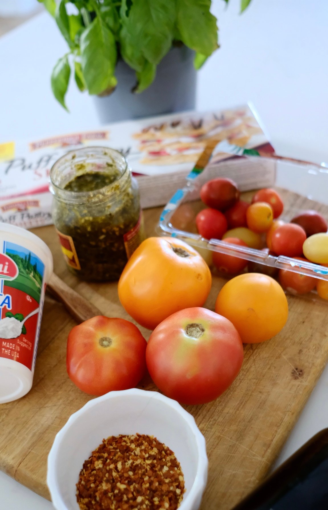 ingredients for a recipe for tomato tart with ricotta and pesto. 