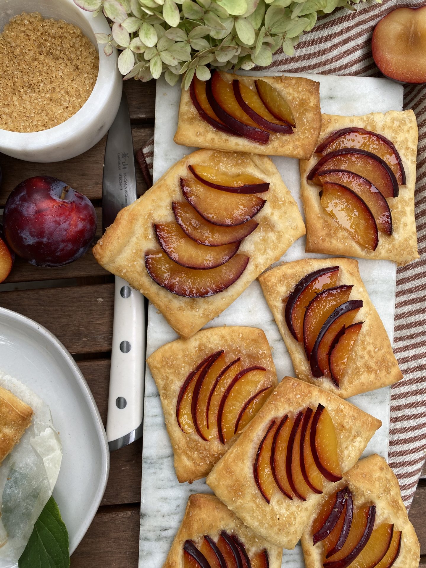 a plate of plum tarts on puff pastry with purple plums. 